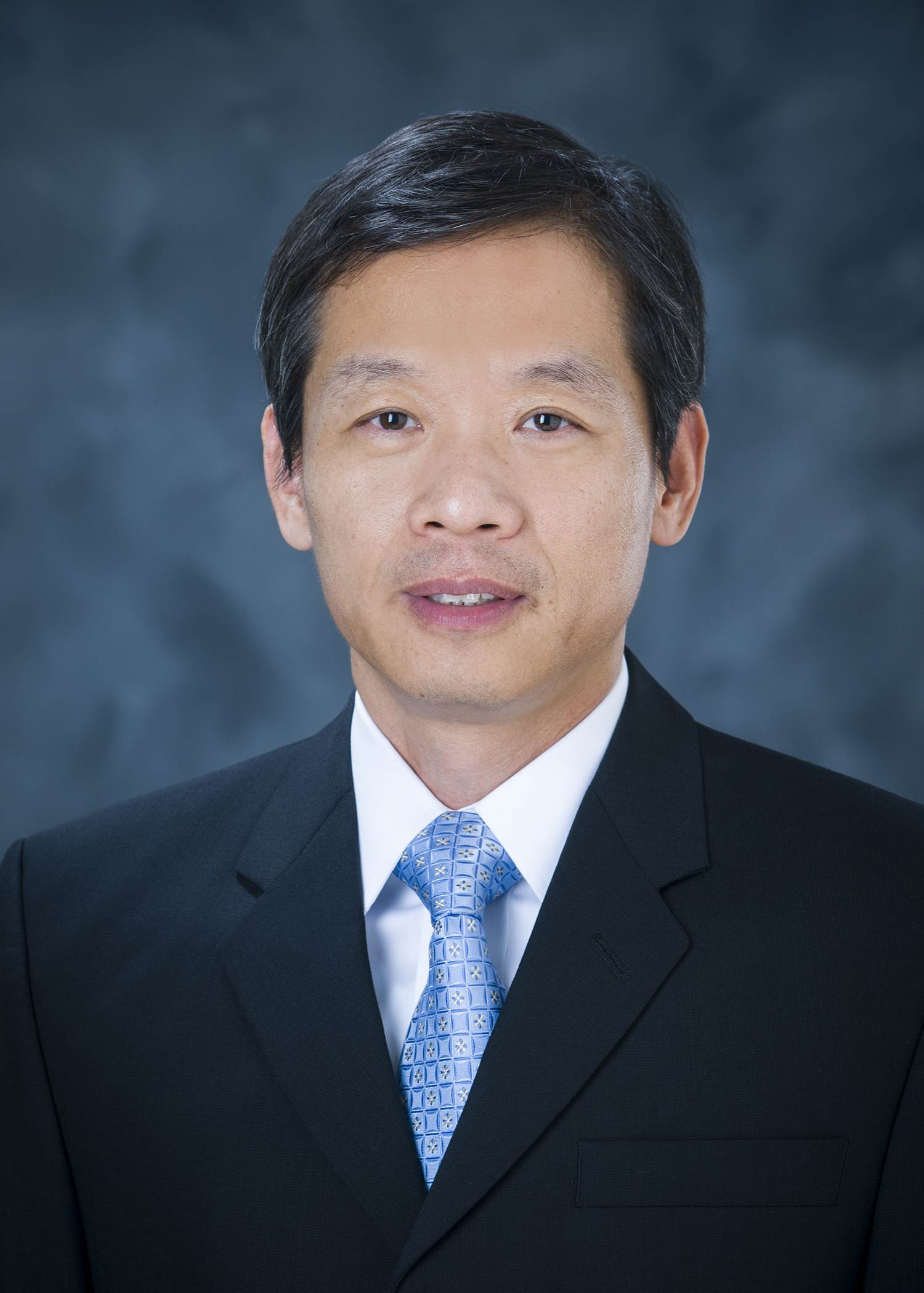 Professional photo of Qingmin Meng, wearing a blue tie and dark suit against a blue background.