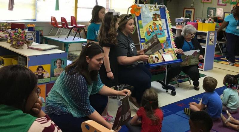 Mrs. Sarah Walker reads to a classroom, assisted by Amy Moe-Hoffman.