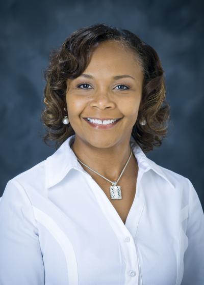 Professional photo of Tina Davis, wearing a white shirt against a blue background.