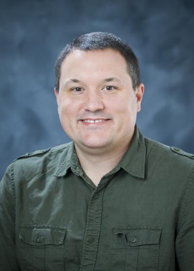 Professional photo of Andrew Mercer wearing a green shirt against a blue background